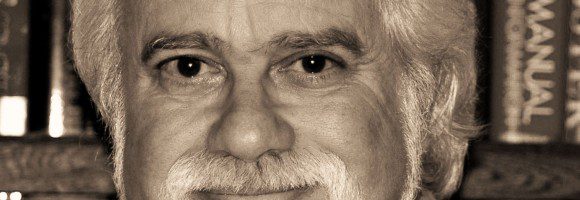 Portrait of an elderly man with white hair and beard, smiling.
